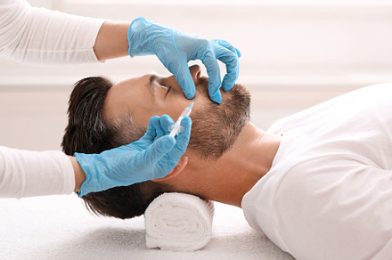 Side view of bearded man getting beauty injection at clinic, a Photo by Prostock-Studio