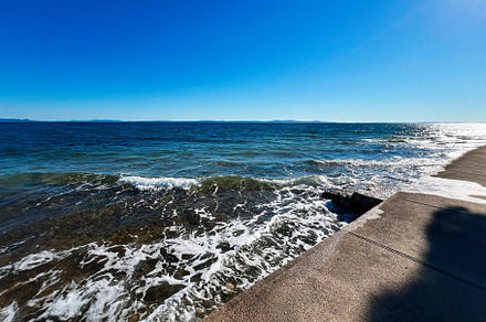 Tranquil ocean waves gently hitting the concrete shoreline, a Photo by AS photostudio