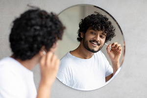 Daily hygiene routine. Indian man cleaning ears using cotton swab while doing m, a Person Photo by Prostock-Studio