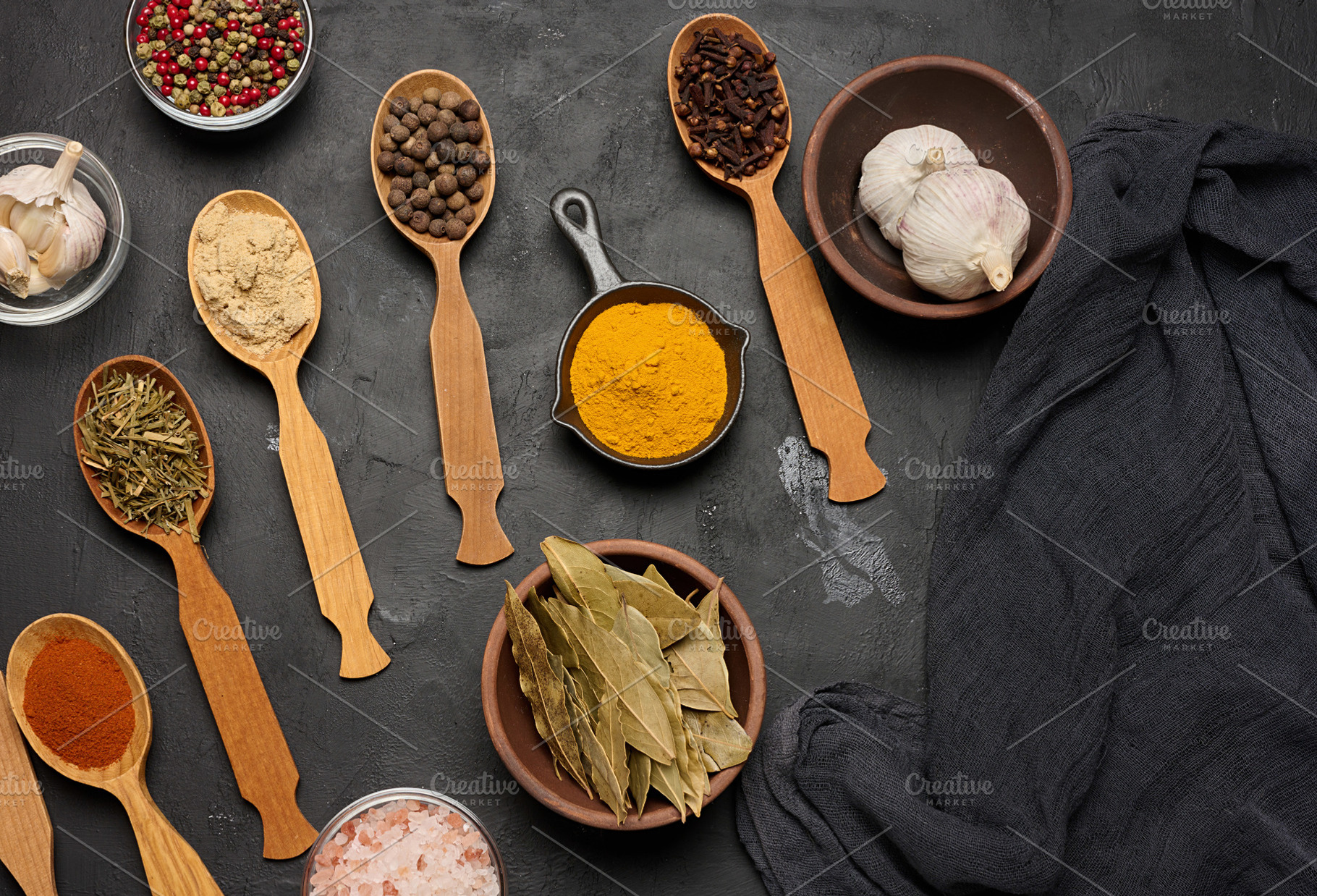 Various ground spices in wooden spoons, peppercorns on dark tabl, a Food & Drink Photo by ndanko