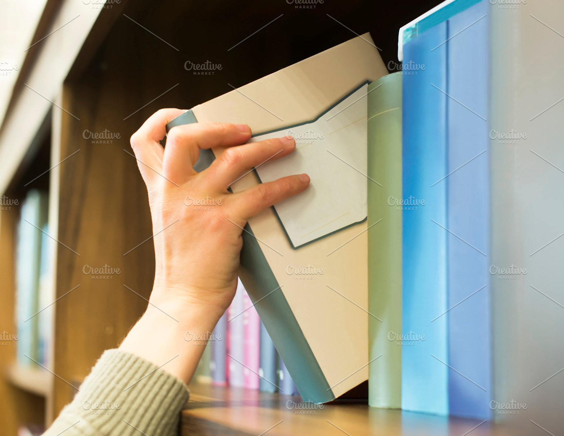 Hand pulling a book off the shelf featuring book, bookcase, and books ...