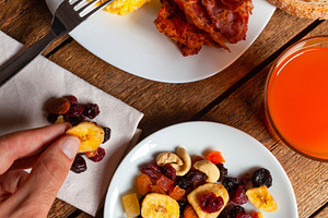 Hand Picking Dried Fruit from Plate, Scrambled Eggs with Bacon and Orange Juice, a Food & Drink Photo by Antonio Gravante Market