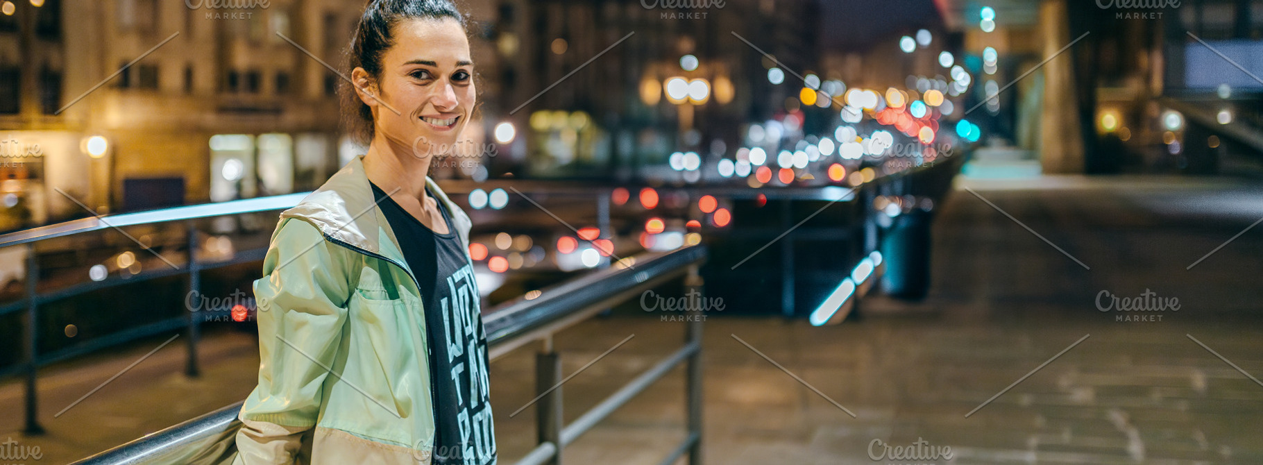 Woman wearing sportswear looking at camera with night town on background, a Sports & Recreation Photo by davidpereiras
