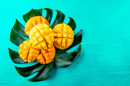 Creative layout made of summer tropical fruits mango and tropical leaves on, a Nature Photo by LARISA BLINOVA