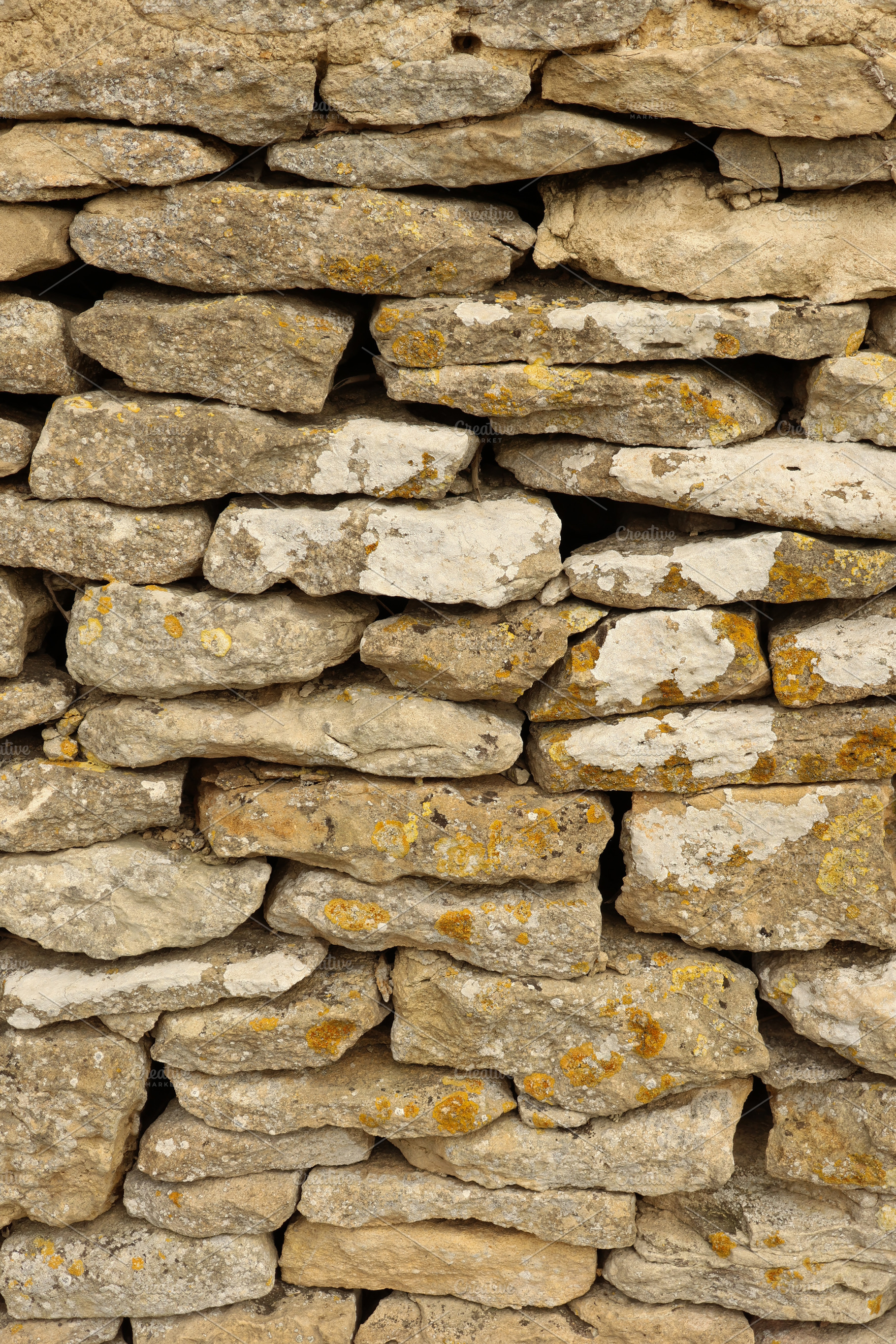 Dry stone walling detail showing rough textured rock surface with various earth, a Photo by Studio ANNA