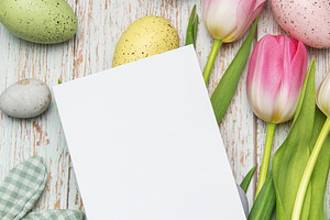 Easter eggs and tulips framing a blank card on rustic wooden bac, a Holiday Photo by Olena Rudo