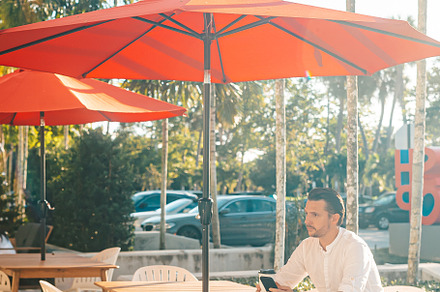 Young man in white shirt working on laptop in outdoor cafe, a Person Photo by travnikovstudio