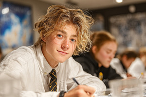 Young student writing notes attentively in classroom during academic session, a Photo by AS photostudio