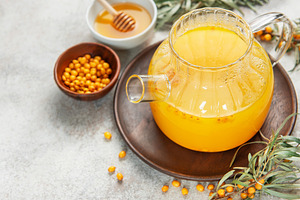 Sea buckthorn hot drink in glass teapot on wooden tray, a Food & Drink Photo by Olena Rudo