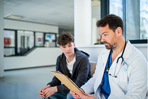 Doctor talking with teenage patient, a Person Photo by HalfPoint