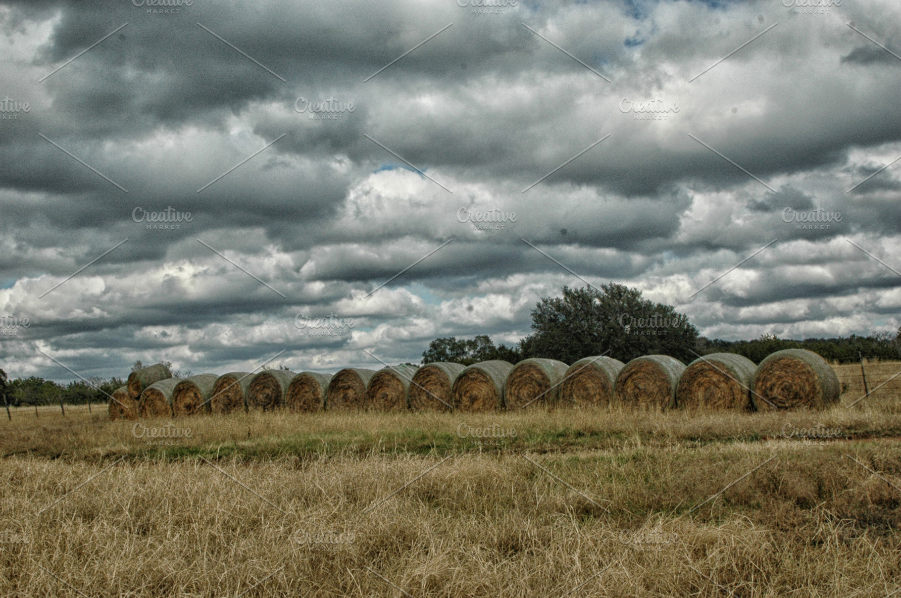 row of hay bales in a gloomy field, a Nature Photo by Claire + Pierre Design