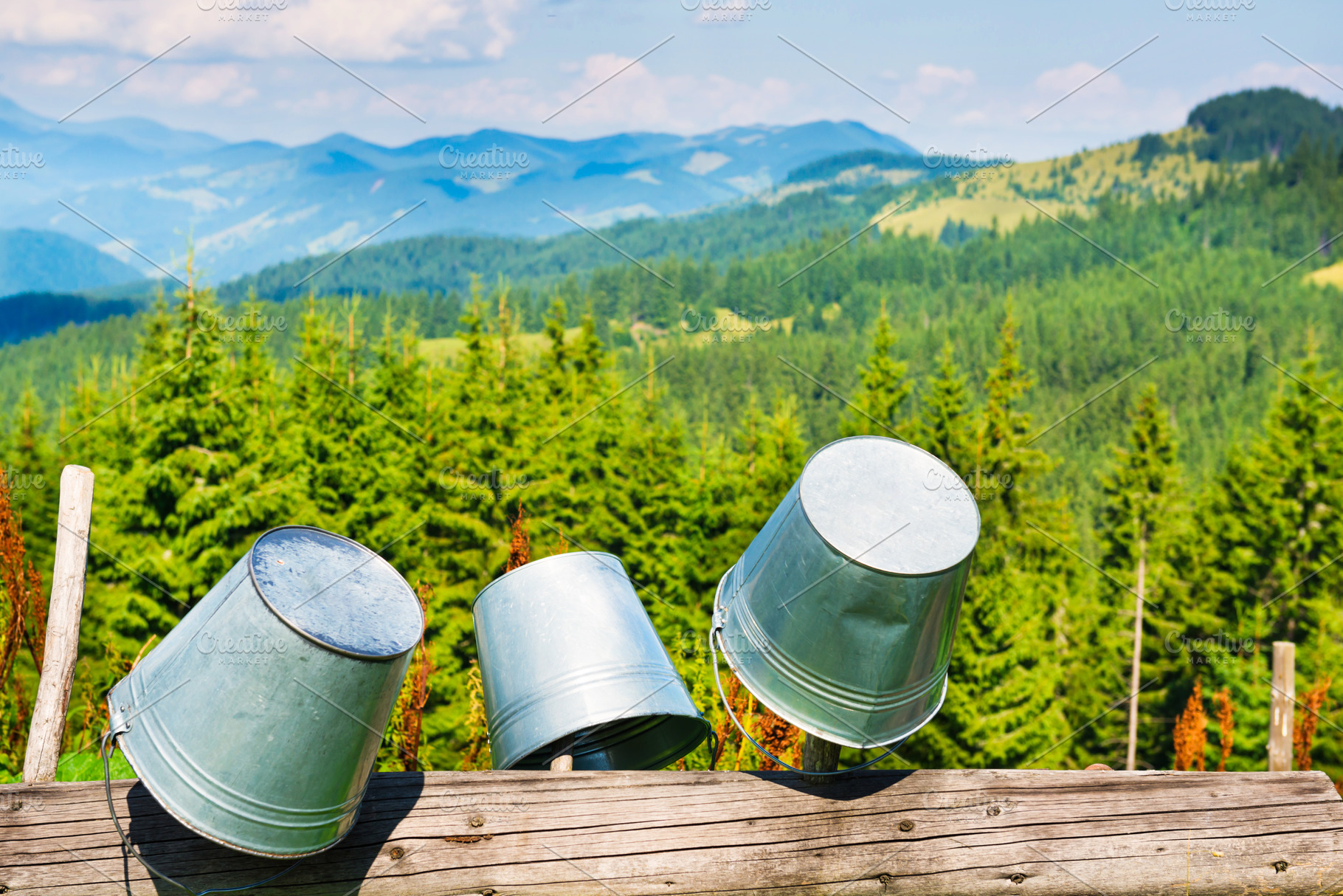 Empty buckets on fence with mountain landscape, a Nature Photo by Vapi