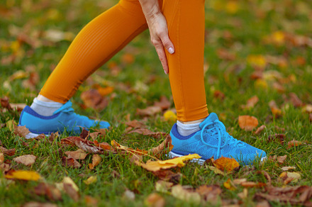 Stylish woman in fitness clothes in park having leg pain, a Sports & Recreation Photo by Alliance Images