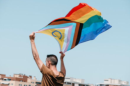waves a progress pride flag in the a, a Person Photo by Nito