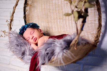 a newborn baby girl, sleeping on a fabric bow with a blue flower headband, a Photo by YossSabalet