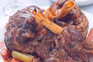 Braised lamb shanks with vegetables on a white plate, vertical closeup, a Food & Drink Photo by iuliia_n