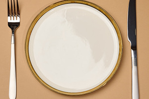 Round white empty ceramic plate and knife with fork on brown bac, a Food & Drink Photo by ndanko