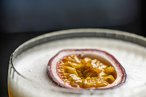 Cocktail with foam, and passion fruit garnish, a Photo by Grafvision photography