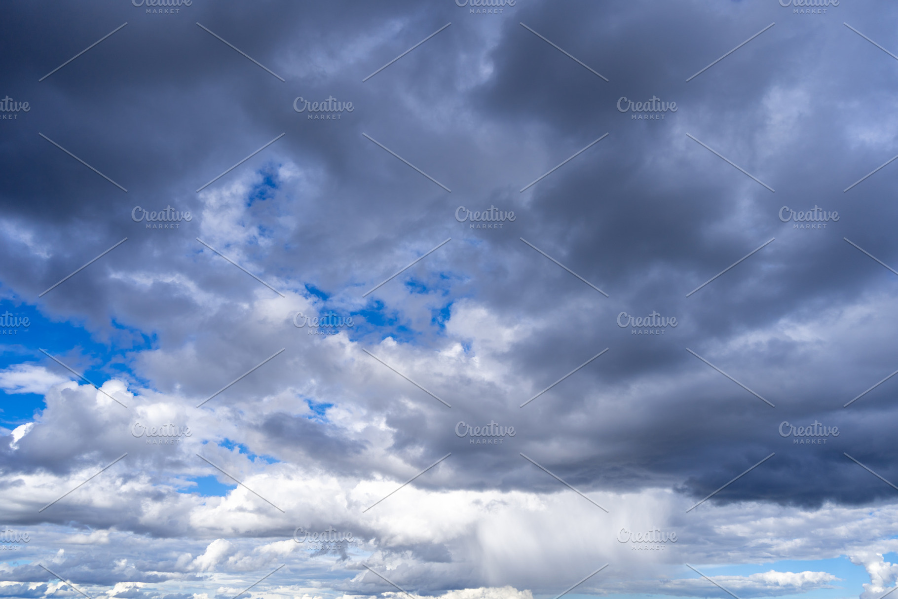 Dark storm clouds with patches of blue sky visible, a Nature Photo by GoodGoods