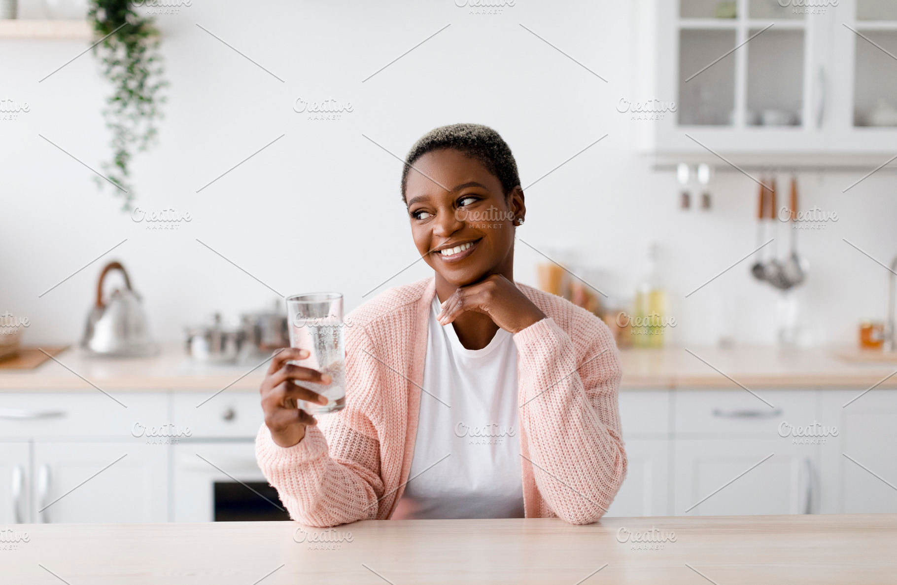 Smiling glad young attractive black lady holds glass of clean water, pensive an, a Person Photo by Prostock-Studio