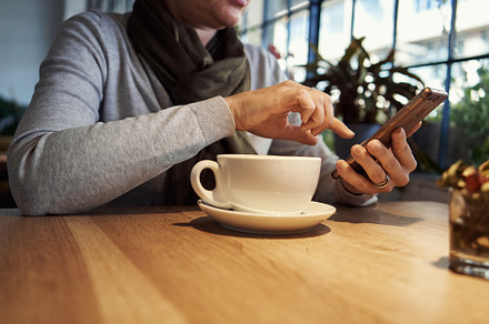 Woman having coffee at a restaurant, looking at her smartphone, a Food & Drink Photo by Madeleine Steinbach