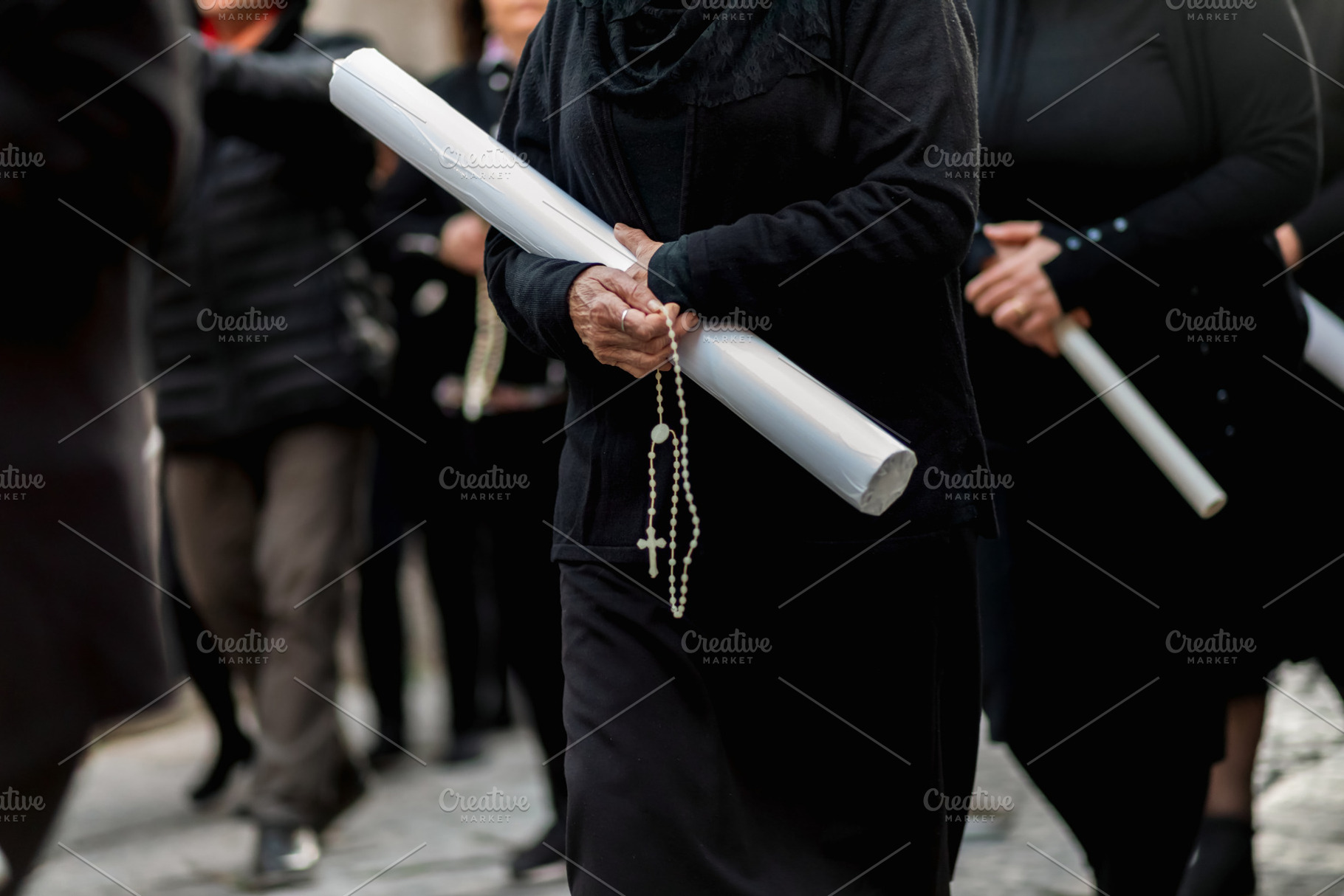 Women holding candles and praying during Good Friday procession, a Holiday Photo by Antonio Gravante Market