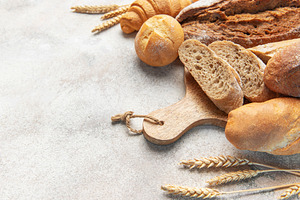 Fresh baked bread assortment with wheat ears on board, a Food & Drink Photo by Olena Rudo