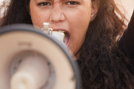 Woman, megaphone and protest in the city for human rights, gender based violence or equality in the outdoors. Female activist shouting, screaming and speaker for discrimination, community or change, a Photo by Peopleimages.com