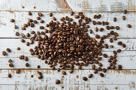 Heap of coffee beans on wooden table, a Food & Drink Photo by AlyaAnd