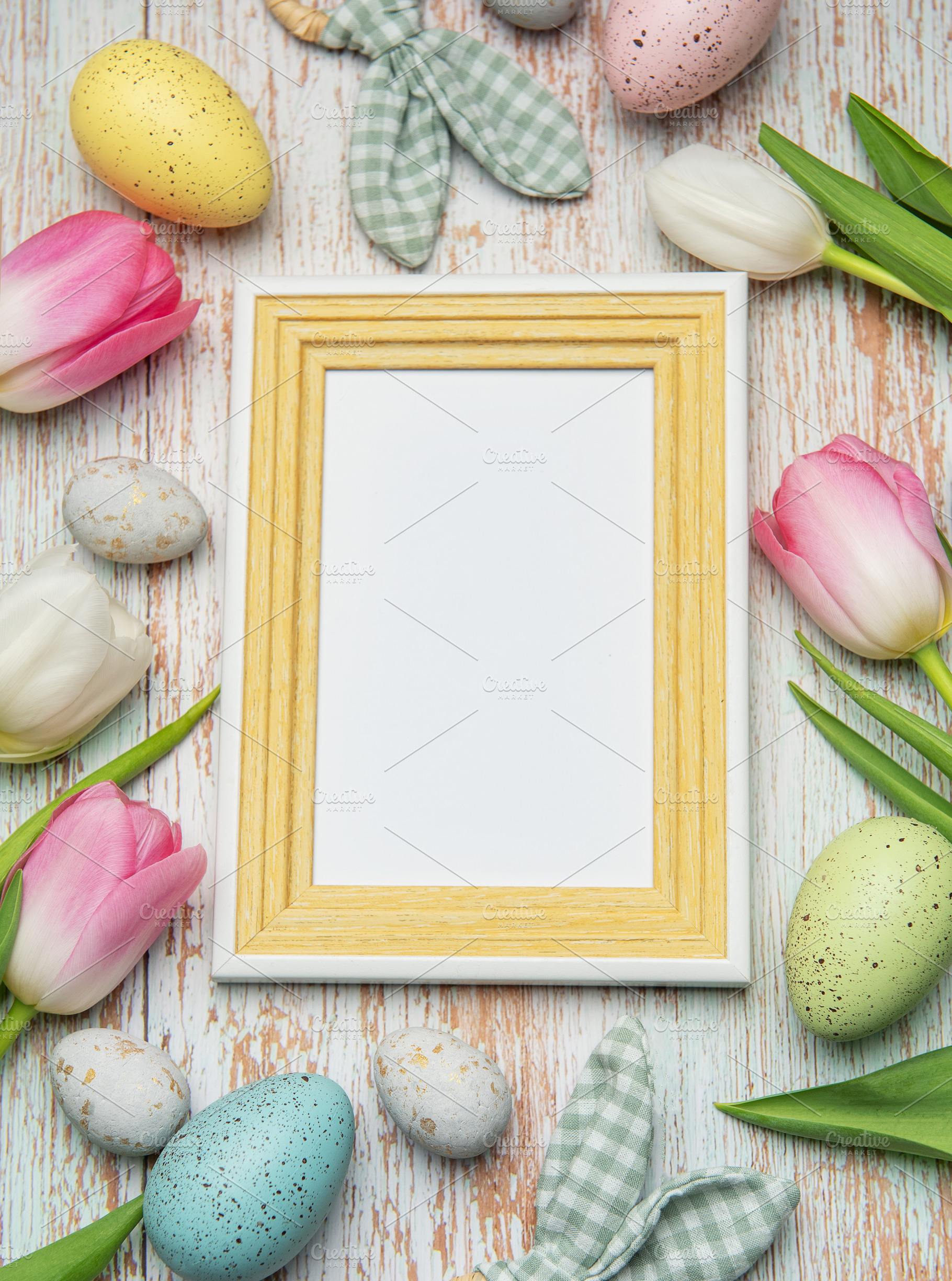 Easter eggs and tulips framing blank picture frame on wooden bac, a Holiday Photo by Olena Rudo