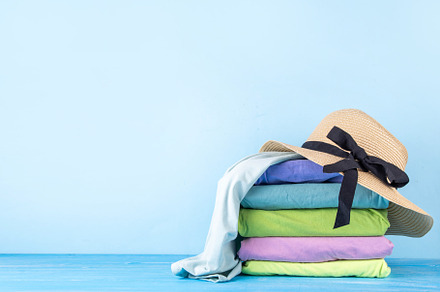 Summer bright clothes pile stack on wooden light blue table, a Holiday Photo by Rimma