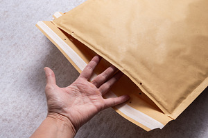 Female Hand Opening Bubble Mailer Plastic Padded Envelope on Whi, an Industrial Photo by MDBildes