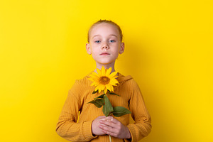 Portrait of a young girl in a yellow sweater holding a sunflower, a Person Photo by Ales Munt