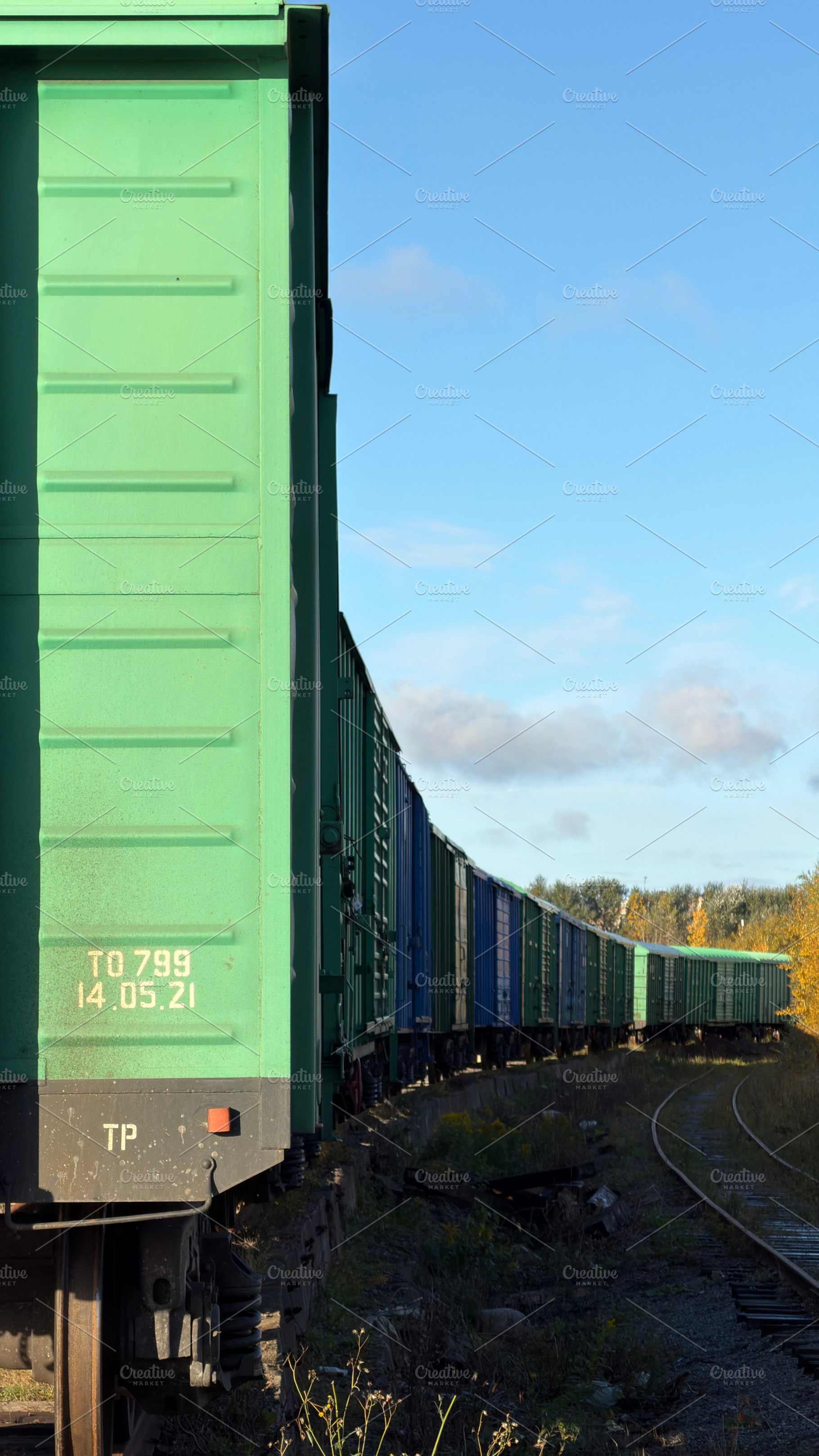 A row of green freight train cars on a railway track under a blue sky, an Industrial Photo by Textures & Backgrounds