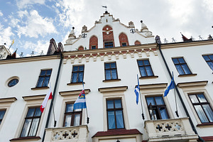 Historic town hall facade with flags and ornate balconies in Rze