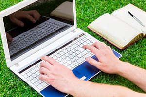 Businessman using a laptop on the grass outdoors green business and