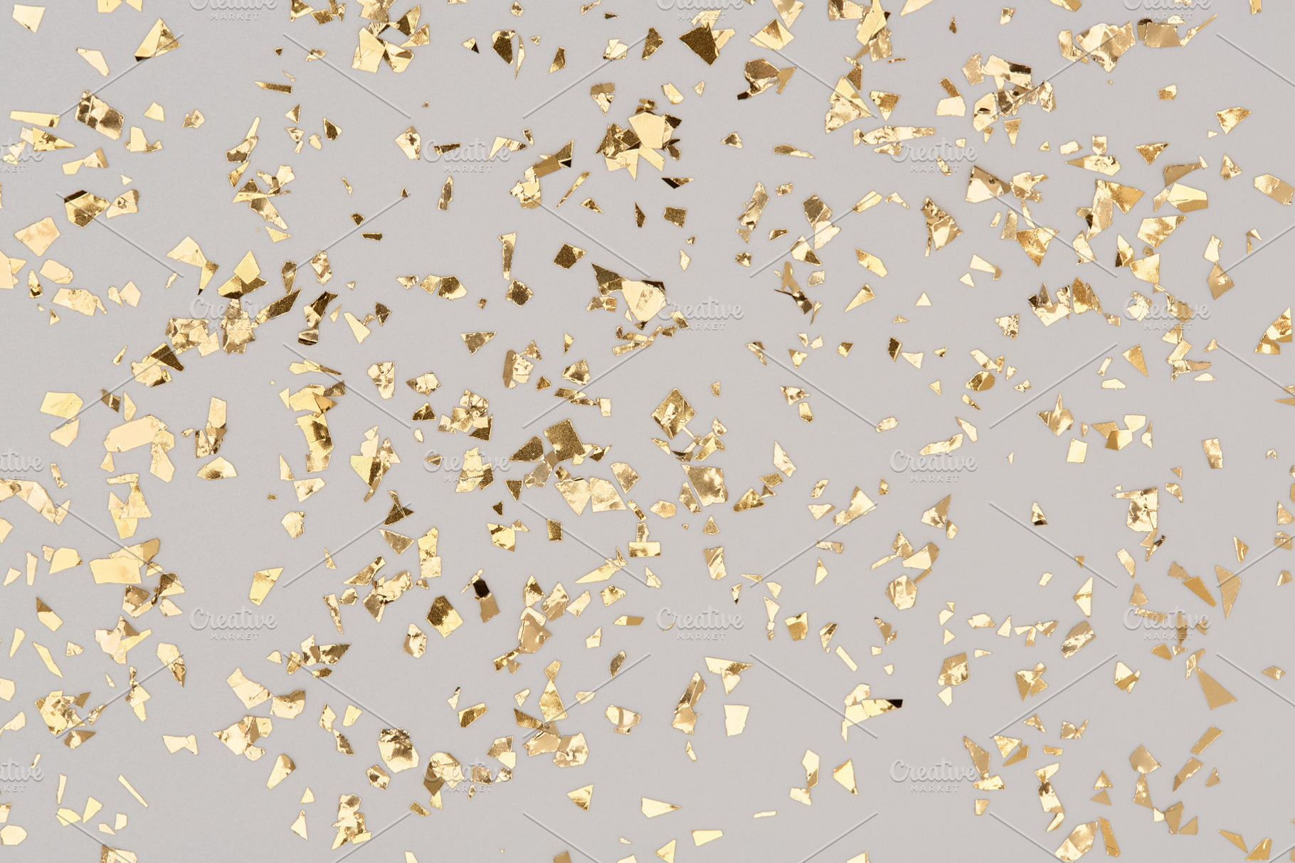 Golden confetti on grey background, an Abstract Photo by Julia Manga