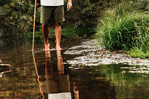 Hiker crossing a stream barefoot in, a Person Photo by Perpis