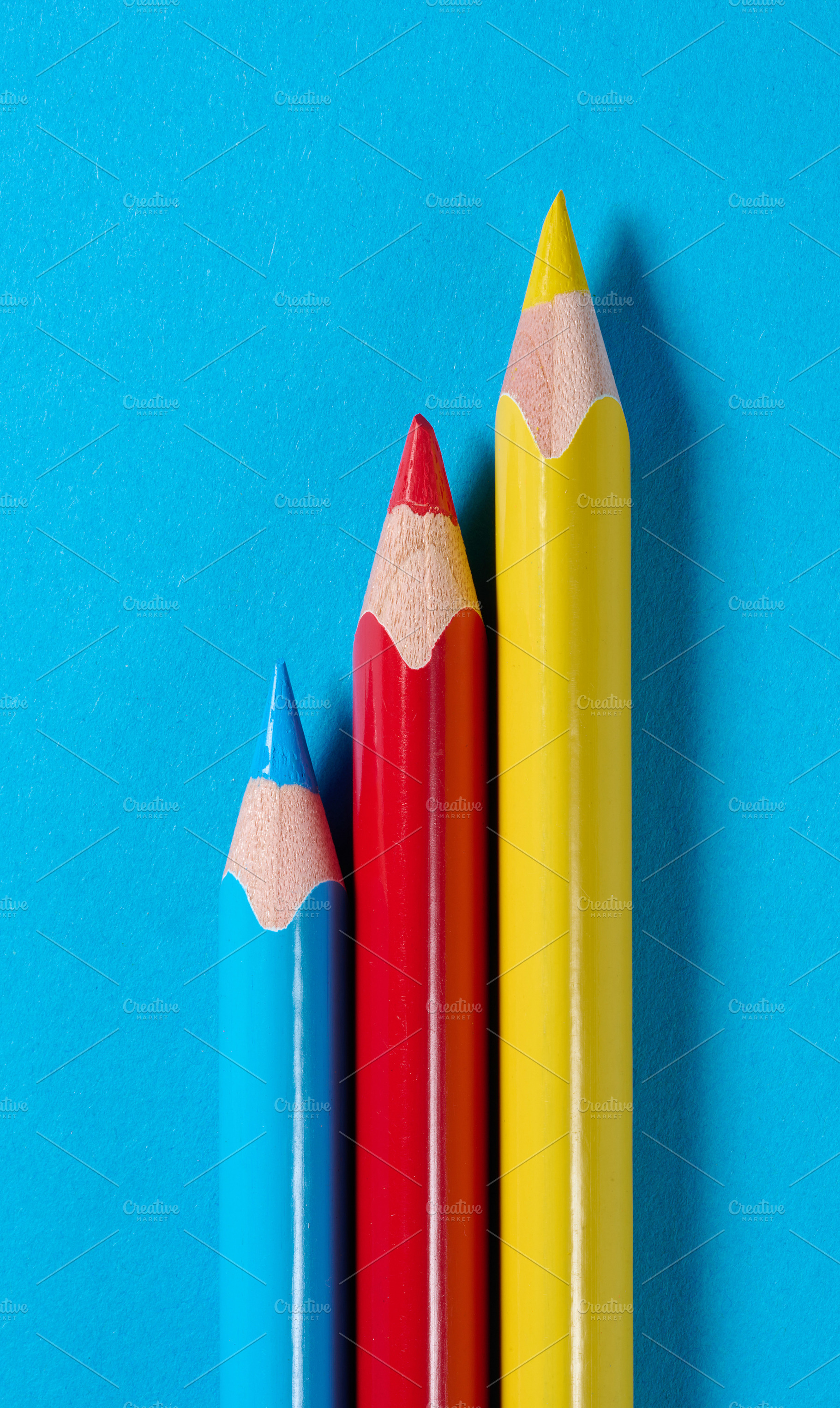 Three colored wooden pencils on a blue background, a School & Education Photo by ndanko