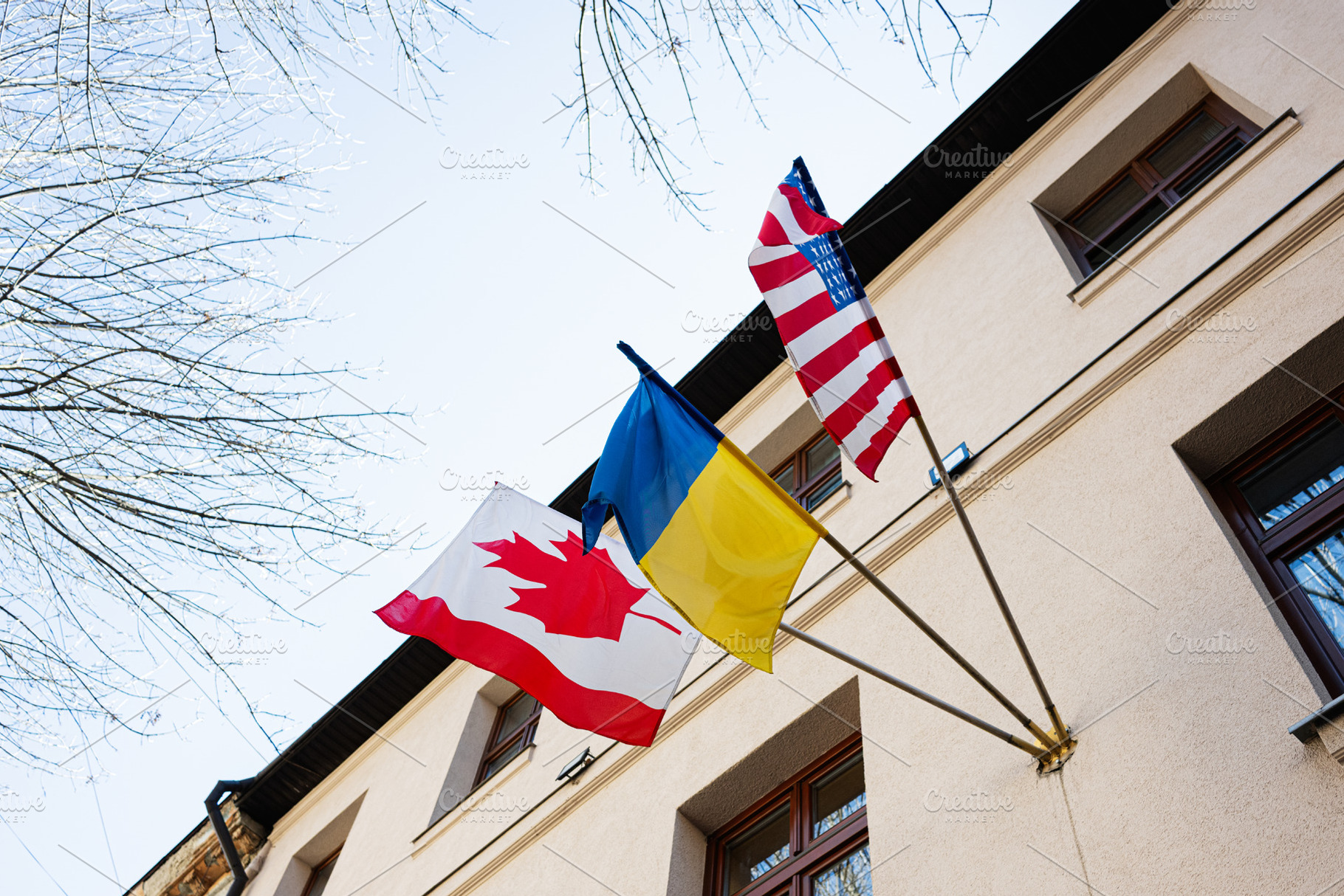 Flags of Canada, USA, and Ukraine displayed outside on a clear sunny day, a Photo by AS photostudio
