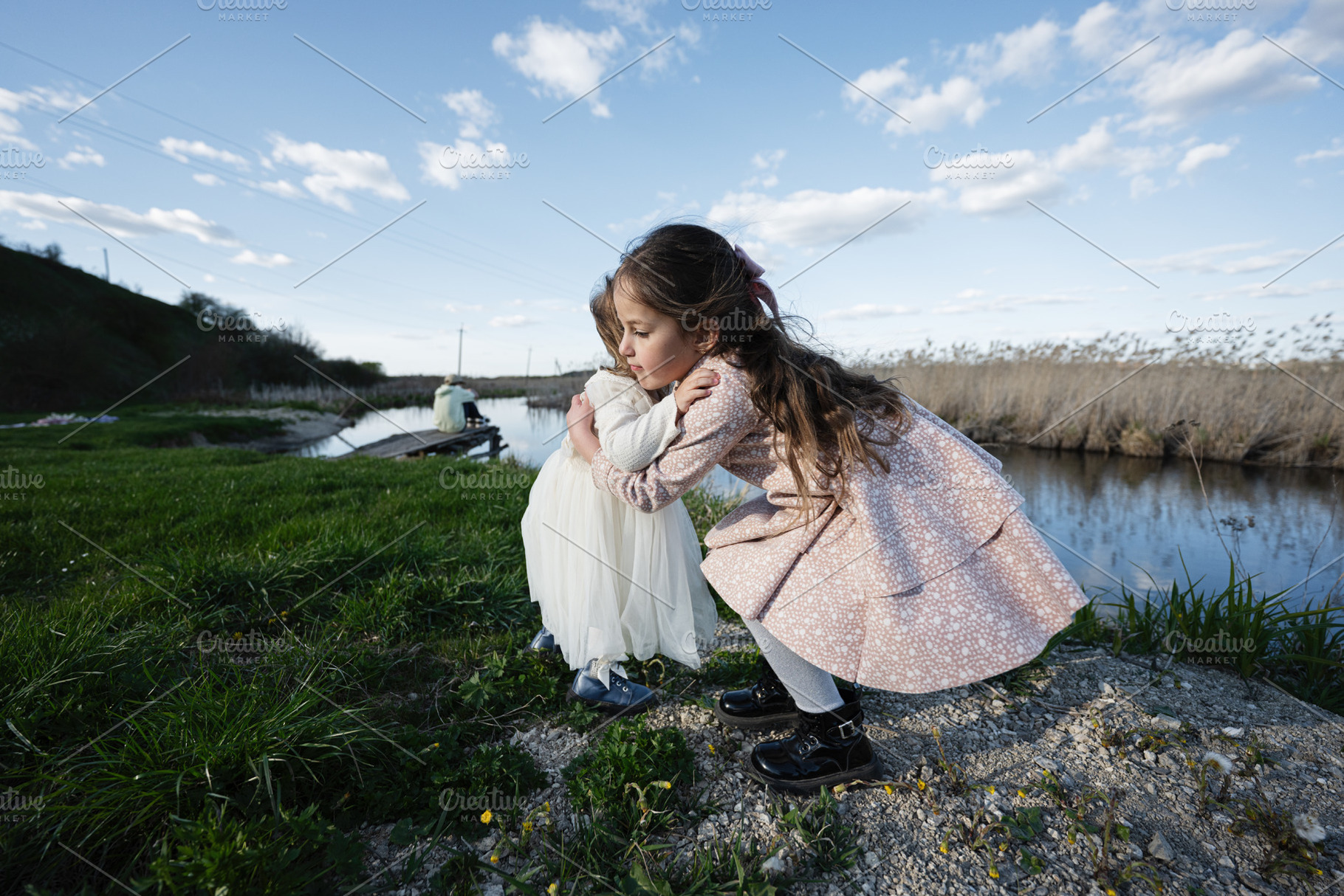 Two young sisters hugging on a river bank in a rural spring landscape with dres, a Person Photo by AS photostudio