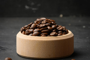 Roasted coffee beans in a wooden bowl on a black background, a Food & Drink Photo by ndanko