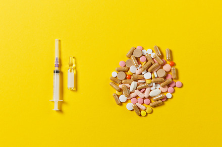 Medication colorful round tablets, capsule, pills arranged abstract on yellow background. Aspirin, ampoule, empty syringe needle. Health, treatment, choice, healthy lifestyle concept. Copy space., a Health & Medical Photo by ViDi Studio
