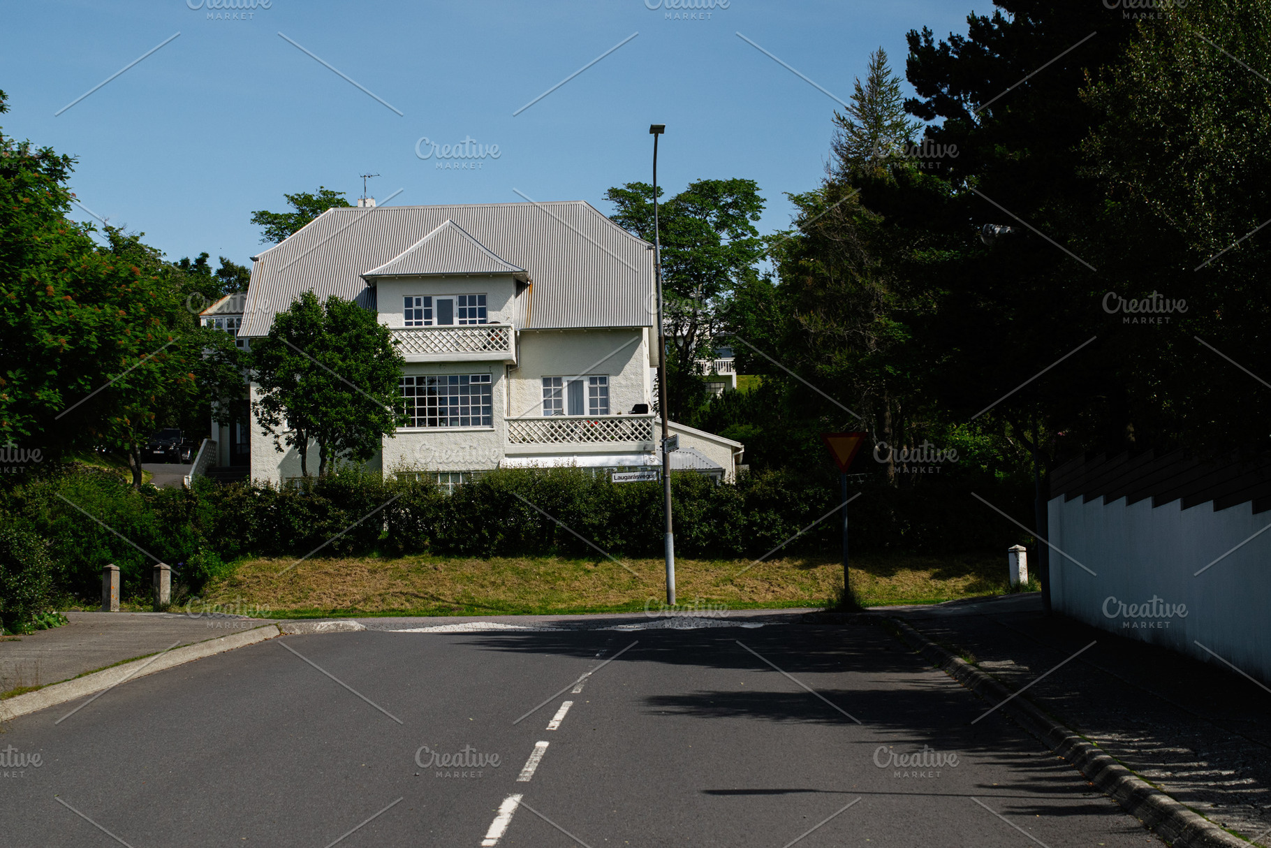 White house surrounded by greenery on a sunny day in Reykjavik, Iceland, a Photo by AS photostudio