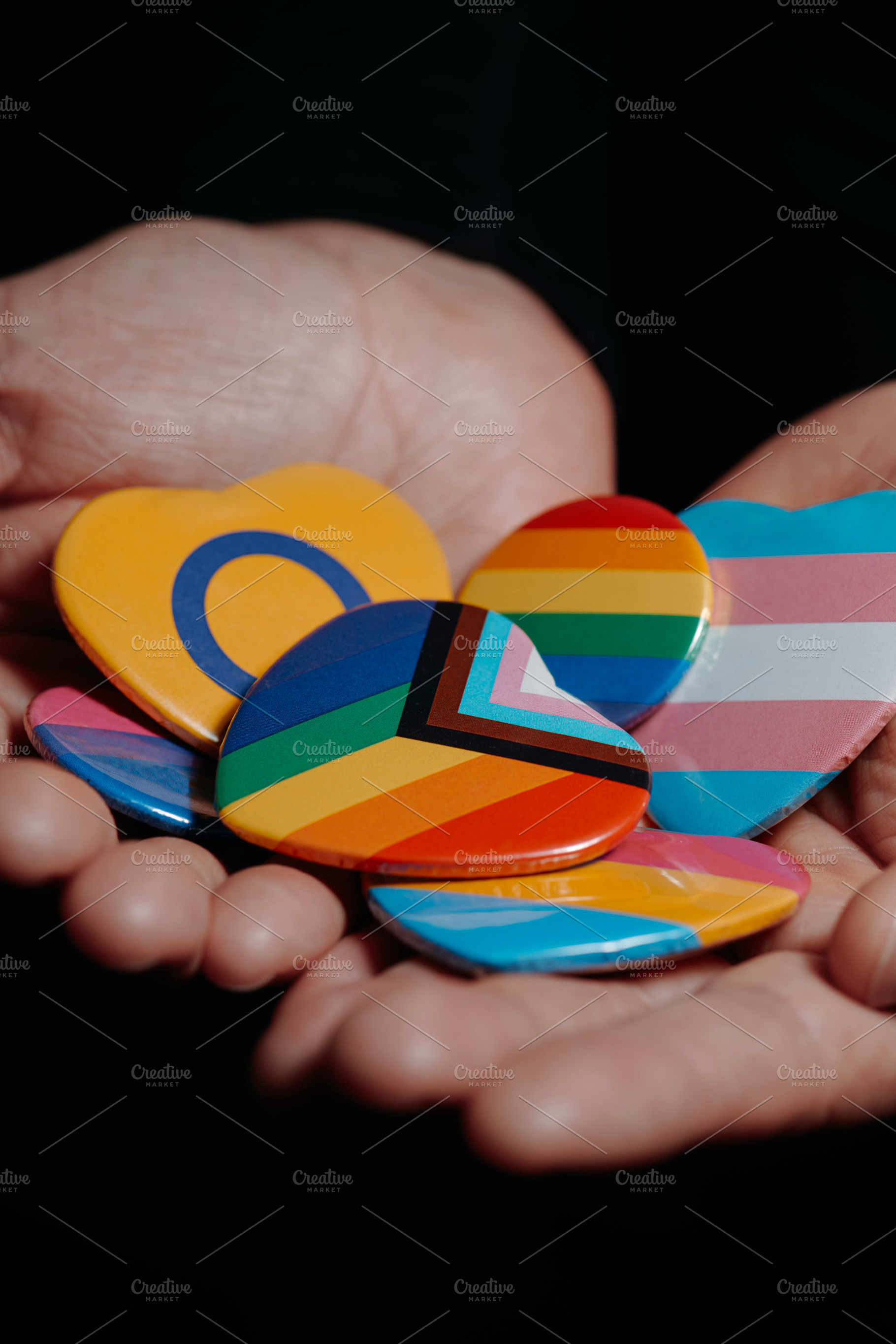 badges with different LGBTQ flags in his hands, a Photo by Nito