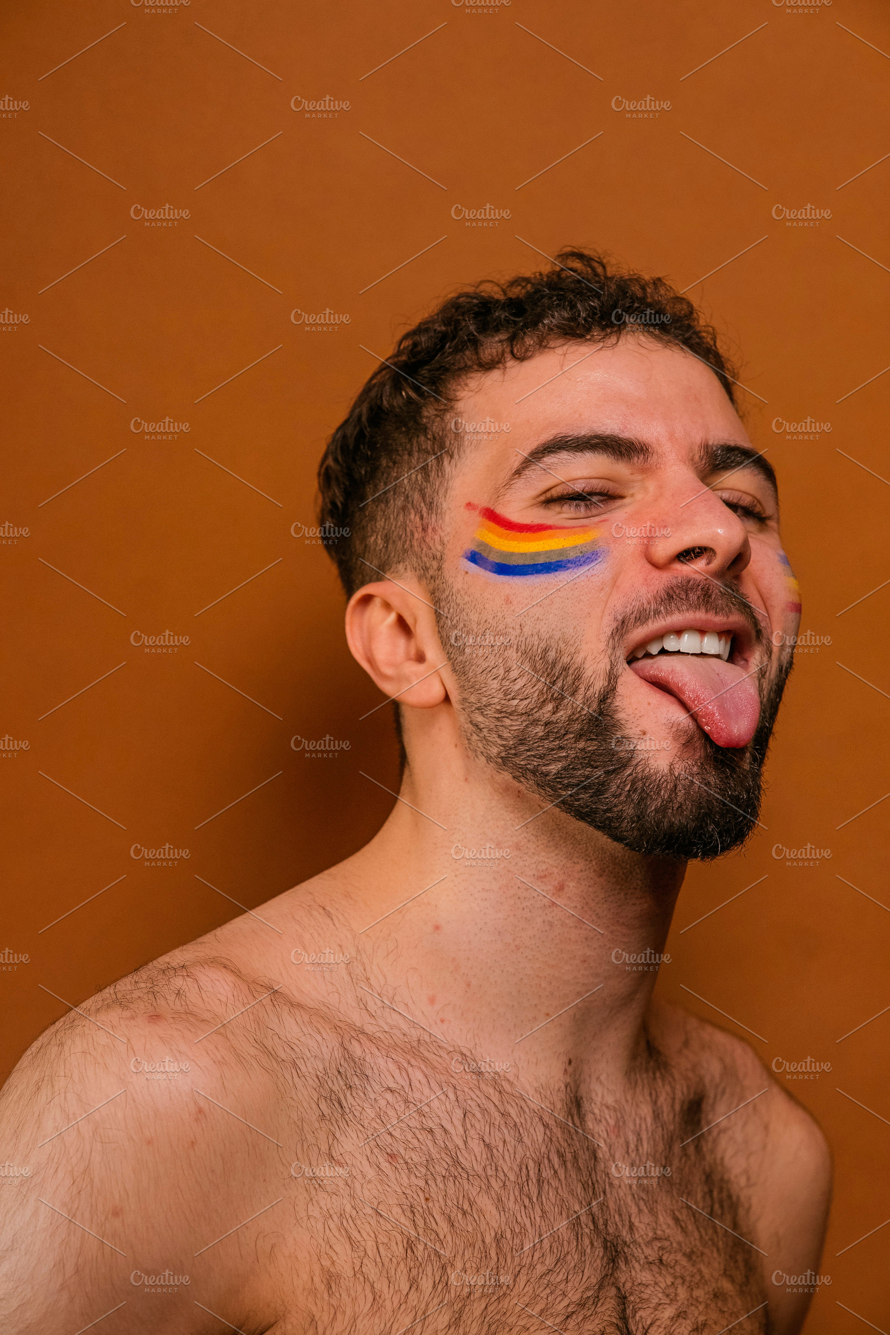 Young adult man smiling with rainbow face paint, a Photo by karrastock