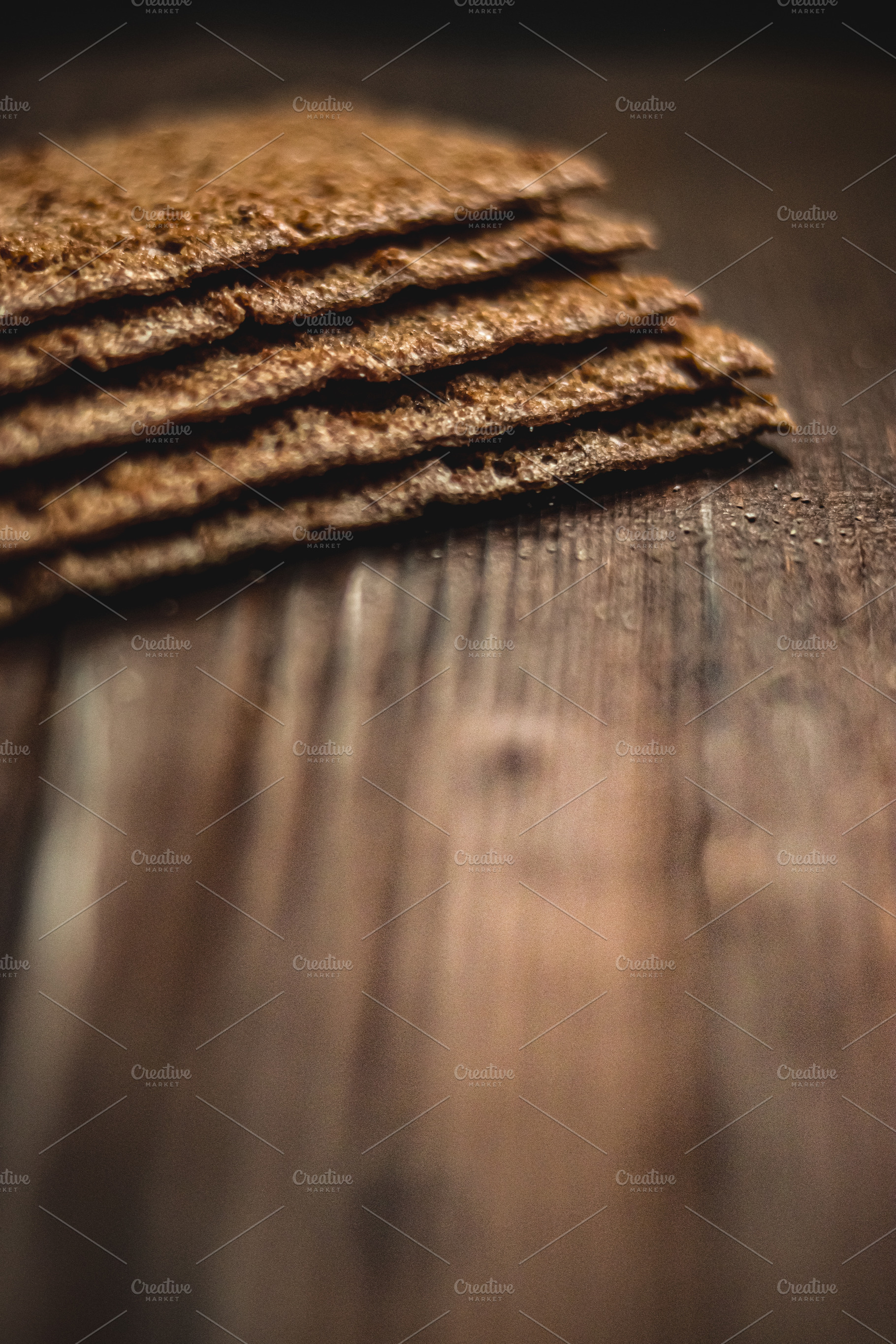 Stacked whole grain crispbread crackers on dark wooden table, showcasing health, a Photo by Studio ANNA