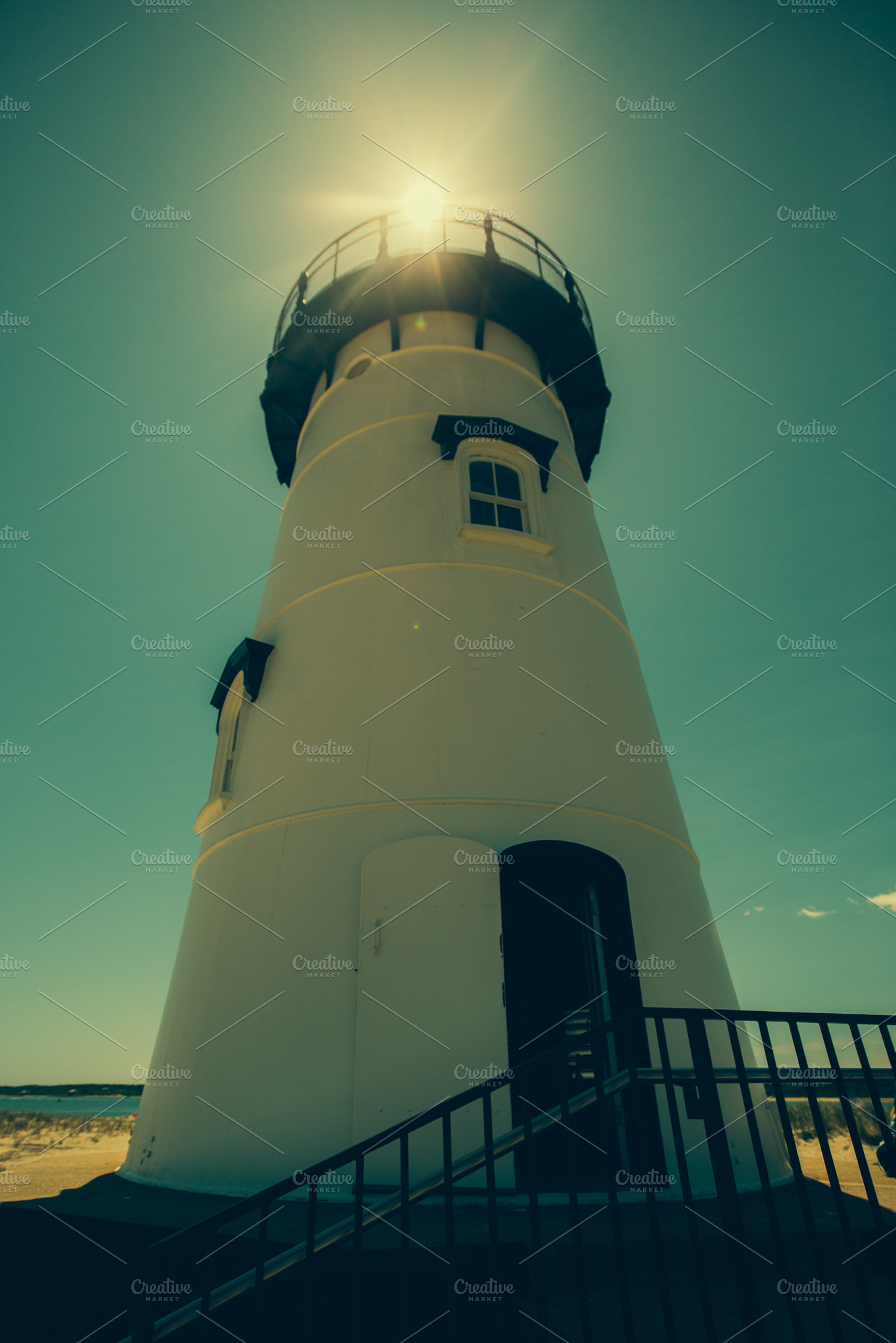 Lighthouse with sun flare featuring lighthouse, sky, and clouds