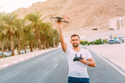 Young man holding drone before flight at nature featuring drone, control, and