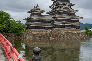 Red bridge leading to majestic Matsumoto Castle in Japan, an Architecture Photo by GoodGoods